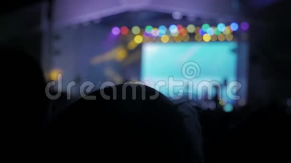 音乐音乐会上的人群在鲜艳的舞台前成群的观众在智能手机上拍照视频的预览图