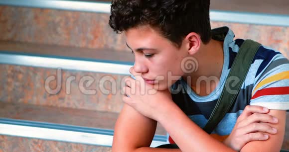 悲伤的小学生独自坐在楼梯上视频的预览图