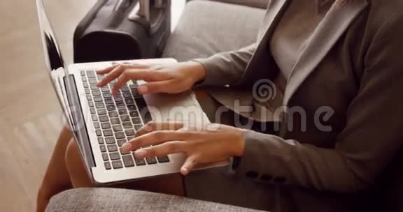微笑的女商人在沙发上用笔记本电脑视频的预览图