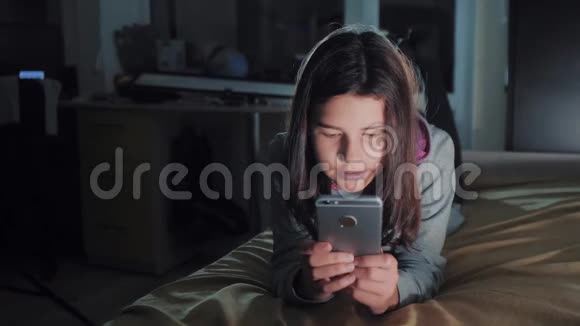 十几岁的女孩网上购物在床上看智能手机生活方式小少年流氓女孩写视频的预览图