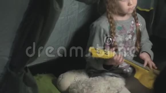 一个漂亮的女孩在一个旅游帐篷附近的河岸上的四弦琴上玩耍视频的预览图