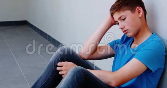 悲伤的小学生坐在走廊里视频的预览图
