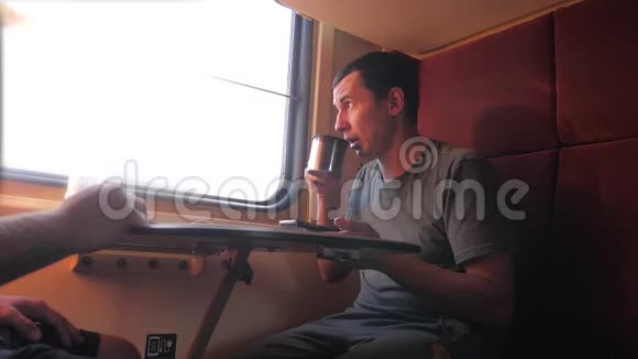 男人坐在火车车厢上手里拿着智能手机铁路喝着咖啡和茶慢速视频视频的预览图