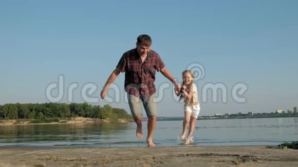 爸爸和女儿一起玩耍的特写镜头一位年轻的父亲正在海边给他的女儿纺纱视频的预览图
