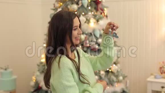 圣诞树附近一个怀孕女孩的肖像视频的预览图