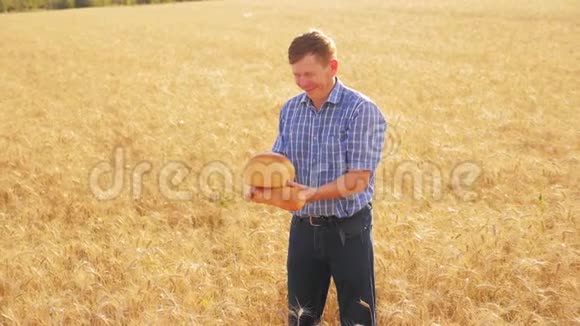 老农夫面包师拿着一个金色的面包和面包在成熟的麦田慢动作视频收获时间旧生活视频的预览图