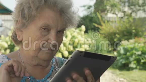 一位在户外手持数码平板电脑的老年妇女视频的预览图