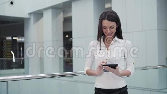 机场候机楼的年轻女乘客在等待航班时使用平板电脑视频的预览图