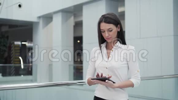 机场候机楼的年轻女乘客在等待航班时使用平板电脑视频的预览图