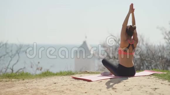 阳光明媚的一天年轻漂亮的女人在海滩上练习瑜伽有魅力的女性冥想视频的预览图