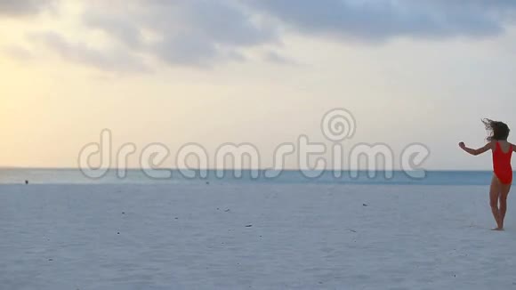 日落时分在白色海滩上可爱的活泼的小女孩剪影视频的预览图