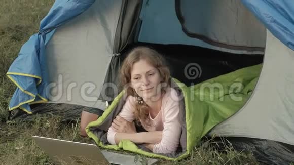 年轻女子在旅游帐篷里的笔记本电脑后面工作视频的预览图