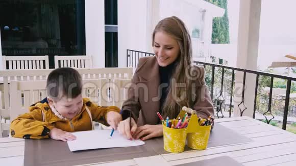 母亲和年幼的儿子在餐桌旁画画视频的预览图