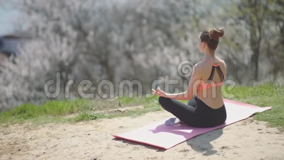 阳光明媚的一天年轻漂亮的女人在海滩上练习瑜伽有魅力的女性冥想视频的预览图