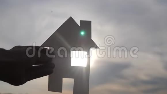 幸福家园建设理念一个男人的生活方式他手里拿着一个纸房子日落时的剪影视频的预览图