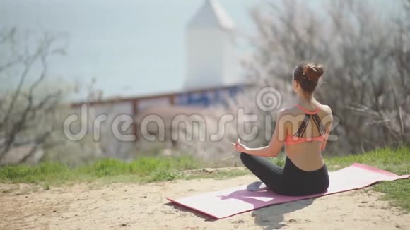 阳光明媚的一天年轻漂亮的女人在海滩上练习瑜伽有魅力的女性冥想视频的预览图