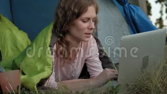 年轻女子在旅游帐篷里的笔记本电脑后面工作视频的预览图