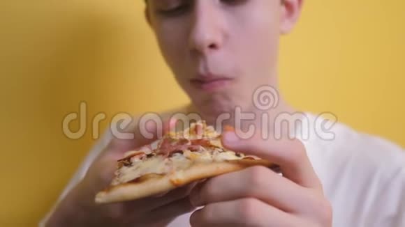 披萨快乐的青少年男孩吃一片披萨的概念小男孩饿了吃一片披萨慢速视频视频的预览图