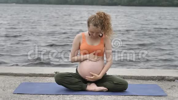 健康的孕妇在户外做瑜伽视频的预览图