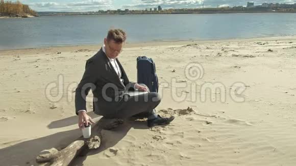 一个带手提笔记本手提箱的商人在海滩上放松视频的预览图