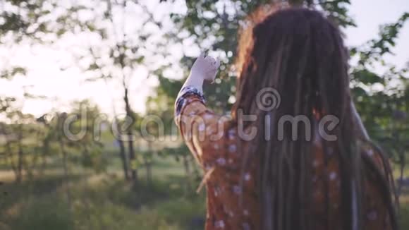 日落时分一位美丽的嬉皮士女人在树林里带着可怕的公鸡在户外玩得很开心视频的预览图