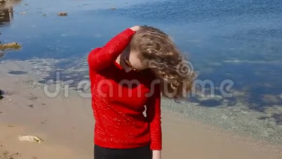 特写一幅女子手挽卷发在沙滩上海风中奔跑的肖像快乐的女人越过蓝天视频的预览图