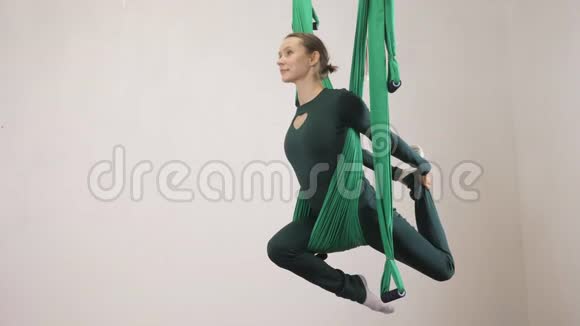 年轻的白种人妇女在室内工作室的吊床上做反重力飞行瑜伽练习航空飞行健身视频的预览图