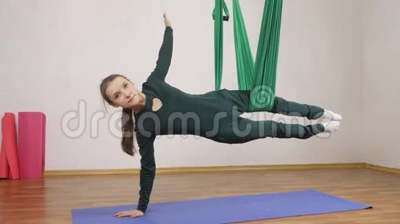 年轻的白种人妇女在室内工作室的吊床上做反重力飞行瑜伽练习航空飞行健身视频的预览图
