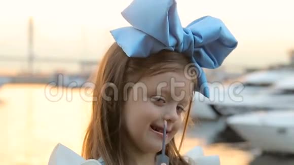 一个小女孩的肖像头上戴着蓝色的蝴蝶结站在水边视频的预览图