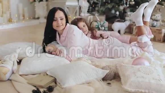 母亲和女儿穿着睡衣在圣诞树附近视频的预览图