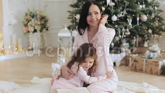 妈妈和女儿穿着睡衣在圣诞树附近视频的预览图