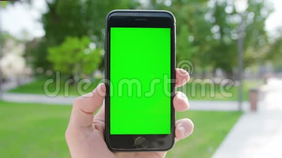 一只手拿着绿色屏幕的手机视频的预览图
