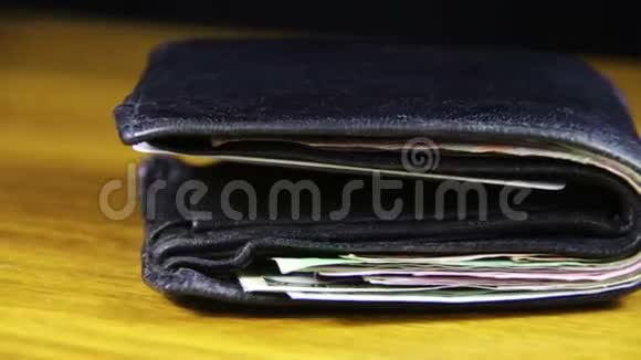 在木桌上旋转的钱包里的钱视频的预览图