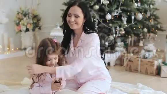 妈妈和女儿穿着睡衣在圣诞树附近视频的预览图