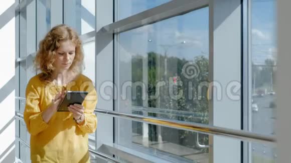 年轻漂亮的女商人靠窗拿着平板电脑视频的预览图