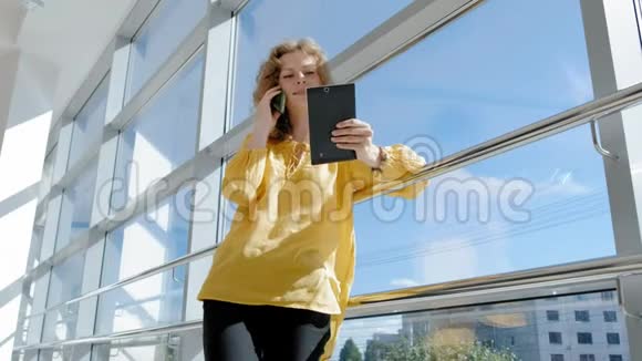 年轻漂亮的女商人靠窗拿着平板电脑视频的预览图