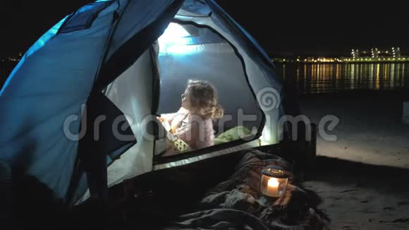 一个美丽的女孩和女人在一个旅游帐篷附近的河岸上的四弦琴上玩耍视频的预览图