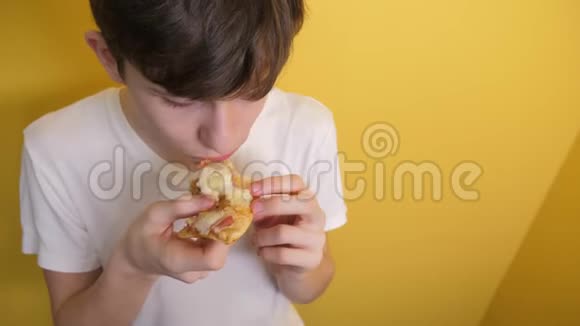 披萨快乐的青少年生活方式男孩吃一片披萨的概念小男孩饿了吃一片披萨慢动作视频的预览图