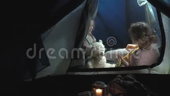 一个美丽的女孩和女人在一个旅游帐篷附近的河岸上的四弦琴上玩耍视频的预览图