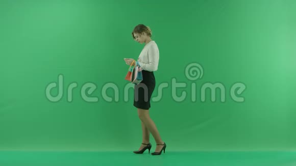 带着购物袋的漂亮购物女人女购物者拿着购物袋侧着绿色背景在工作室视频的预览图