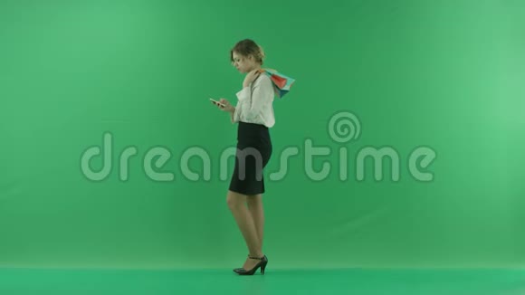 带着购物袋的漂亮购物女人女购物者拿着购物袋侧着绿色背景在工作室视频的预览图