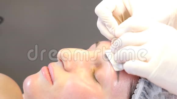 美容诊所美容师用手套在女性皮肤上进行面部老化注射一个女人得到美丽的脸视频的预览图