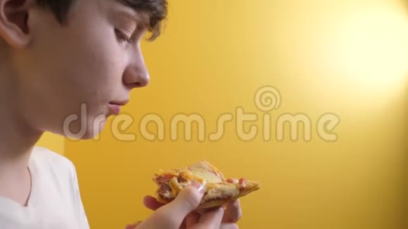 披萨快乐的小男孩吃一片披萨的概念年轻男孩的生活方式饥饿吃一片披萨慢动作视频的预览图