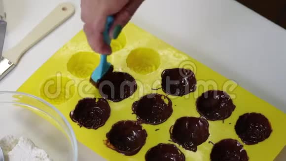 女人用硅胶模具润滑融化的巧克力视频的预览图
