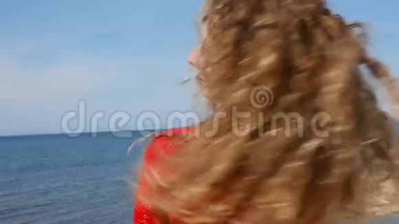 特写一幅女子手挽卷发在沙滩上海风中奔跑的肖像蓝天上快乐的女性视频的预览图