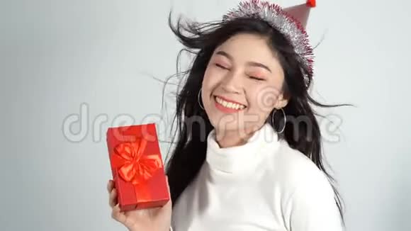 戴着帽子拿着红色圣诞礼盒的快乐女人视频的预览图