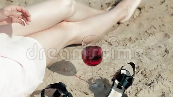 年轻的金发女郎穿着一件漂亮的裙子在海边享受一杯粉红色的葡萄酒动作非常缓慢视频的预览图