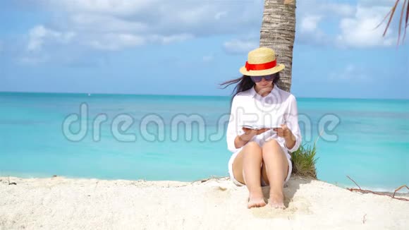 热带白海滩的年轻女子读书视频的预览图