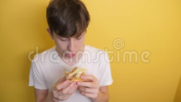 披萨生活方式快乐的青少年男孩吃一片披萨的概念十几岁的男孩饿了吃一片披萨慢动作视频的预览图