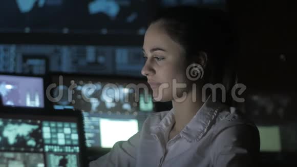 一幅年轻女性程序员在数据中心的一台电脑上工作的画像里面装满了显示屏视频的预览图